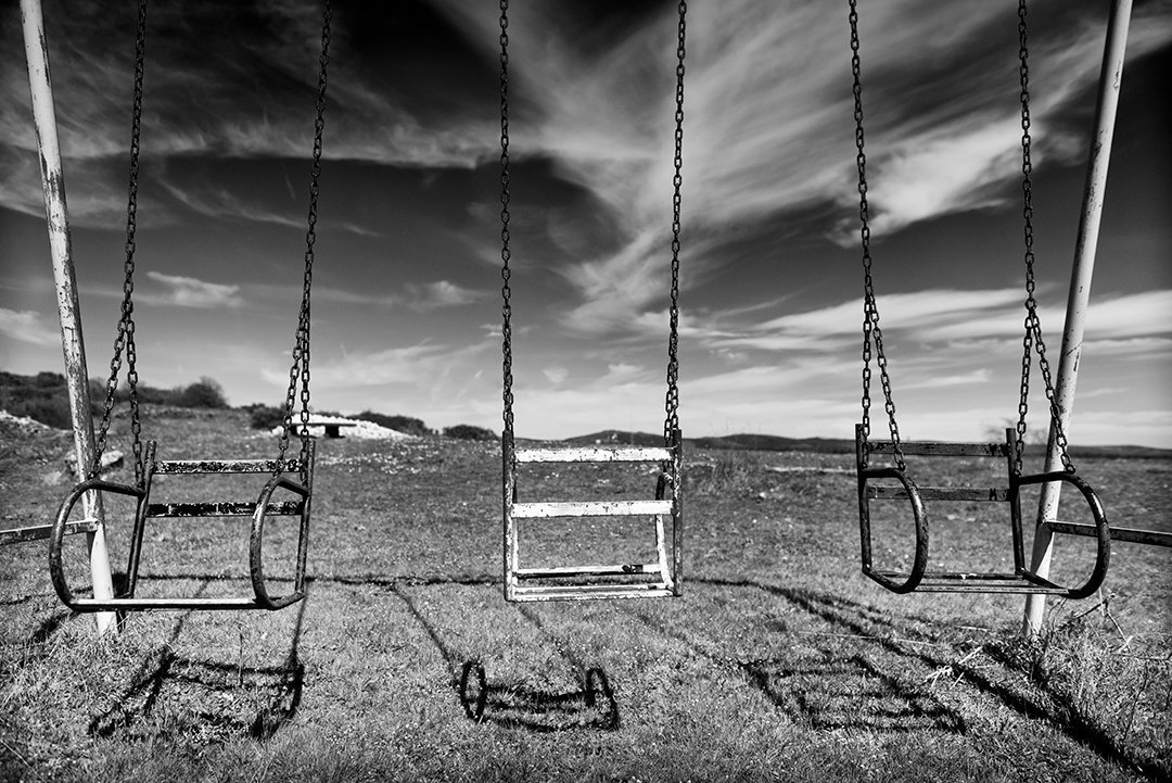 Empty swings in front of an open landscape.